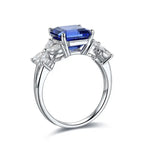 Load image into Gallery viewer, Elegant silver ring featuring a prominent blue gemstone flanked by clear diamonds.
