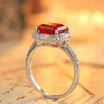 Load image into Gallery viewer, Elegant silver ring featuring a rectangular red gemstone surrounded by smaller clear stones.
