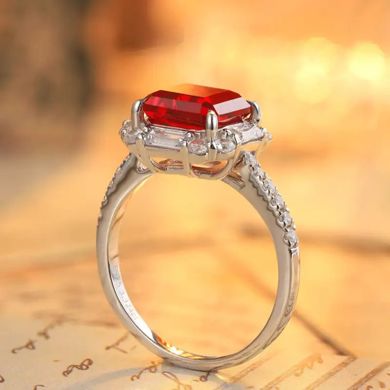 Elegant silver ring featuring a rectangular red gemstone surrounded by smaller clear stones.