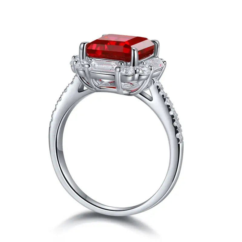 Silver ring with a prominent square-cut red gemstone surrounded by smaller clear stones.