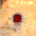 Load image into Gallery viewer, Ornate ring featuring a square-cut ruby surrounded by diamonds in a halo setting.
