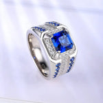 Load image into Gallery viewer, Ornate silver ring featuring a square-cut blue gemstone surrounded by smaller blue and clear stones.
