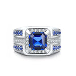 Load image into Gallery viewer, Ornate silver ring featuring a square-cut blue sapphire center stone surrounded by diamonds and smaller sapphires.
