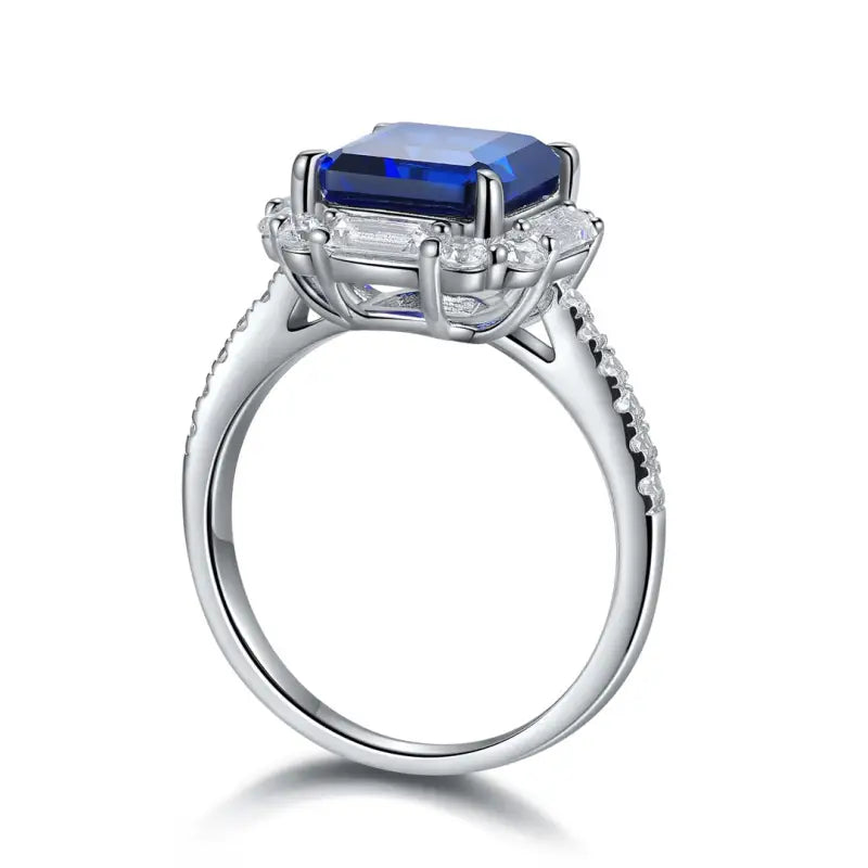 Silver ring featuring a prominent rectangular blue gemstone surrounded by smaller clear stones.