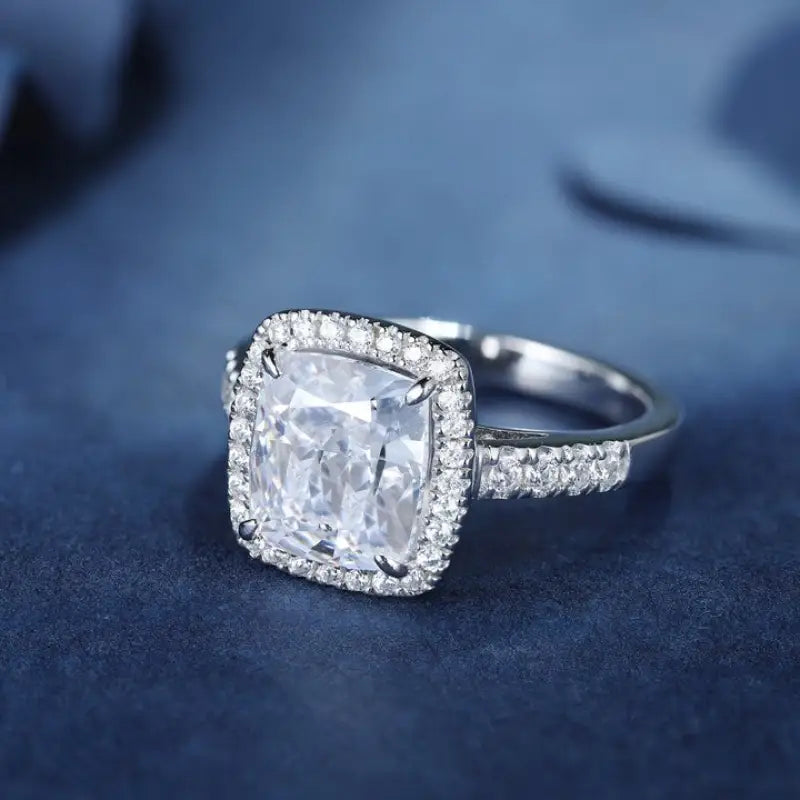 Diamond engagement ring with a cushion-cut center stone surrounded by a halo of smaller diamonds on a pave band.