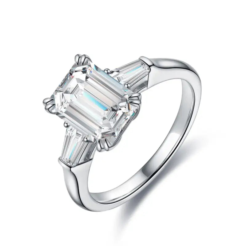 Diamond engagement ring with an emerald-cut center stone and tapered baguette side stones set in a white metal band.