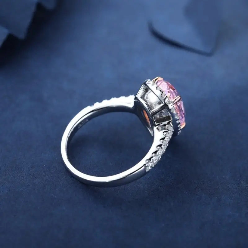 Silver ring with a pink gemstone in an ornate setting.