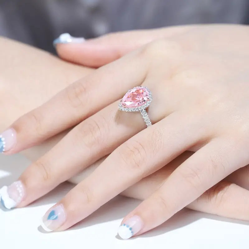 Pink heart-shaped diamond ring on a woman’s finger.