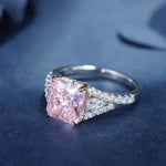 Load image into Gallery viewer, Engagement ring featuring a square-cut pink diamond center stone with smaller white diamonds on the band.
