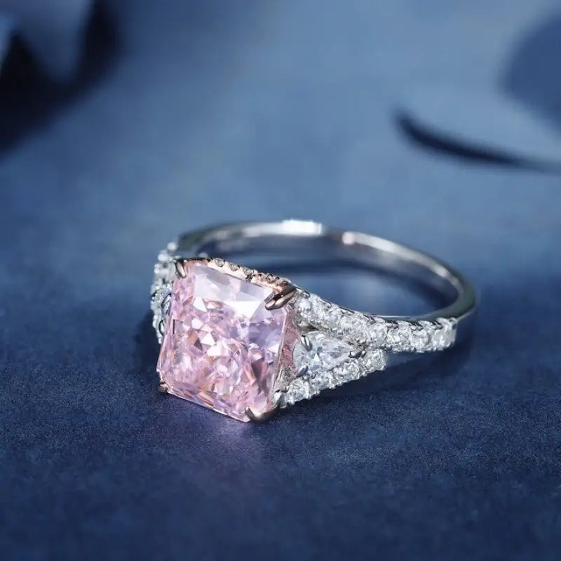 Engagement ring featuring a square-cut pink diamond center stone with smaller white diamonds on the band.