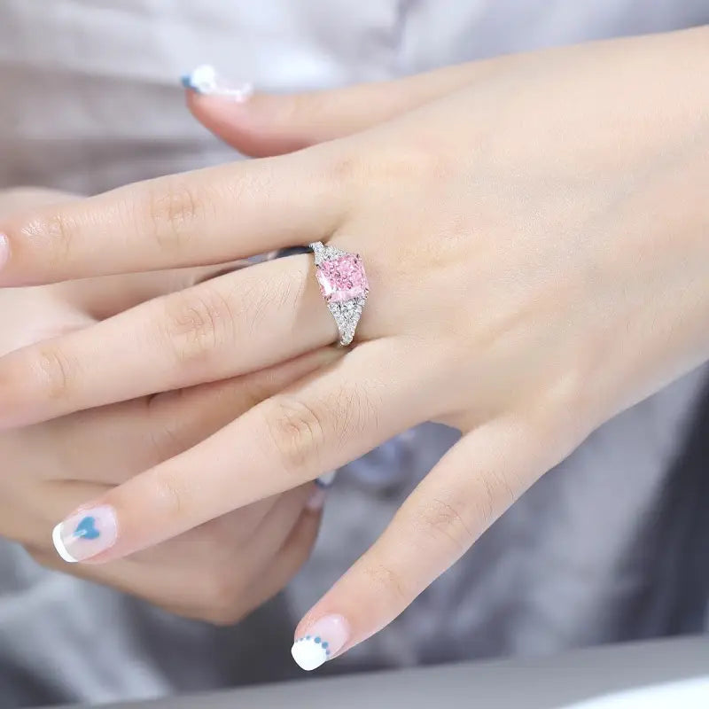 Pink and white diamond ring on a person’s finger.