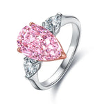 Load image into Gallery viewer, Engagement ring featuring a pear-shaped pink diamond flanked by two smaller white diamonds.
