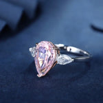 Load image into Gallery viewer, Pear-shaped pink diamond ring with side accent stones set in a silver band.
