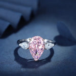 Load image into Gallery viewer, Elegant ring featuring a pear-shaped pink diamond flanked by two white diamonds.
