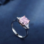 Load image into Gallery viewer, Engagement ring featuring a pink diamond center stone flanked by two smaller white diamonds.
