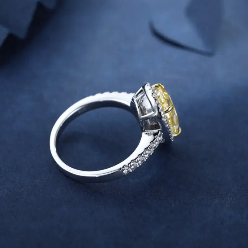 Elegant diamond ring with a yellow center stone set in white metal.