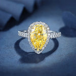 Load image into Gallery viewer, Pear-shaped yellow diamond ring with a halo of smaller white diamonds set in a silver or white gold band.
