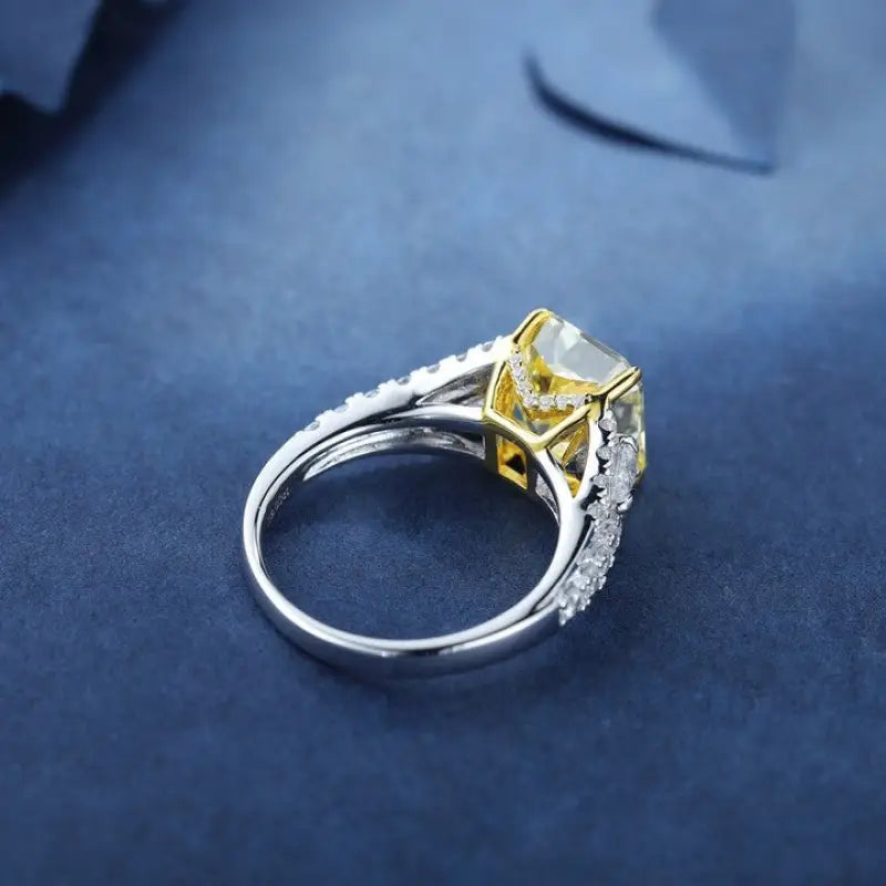 Diamond engagement ring with a yellow center stone and white diamond accents on a silver band.