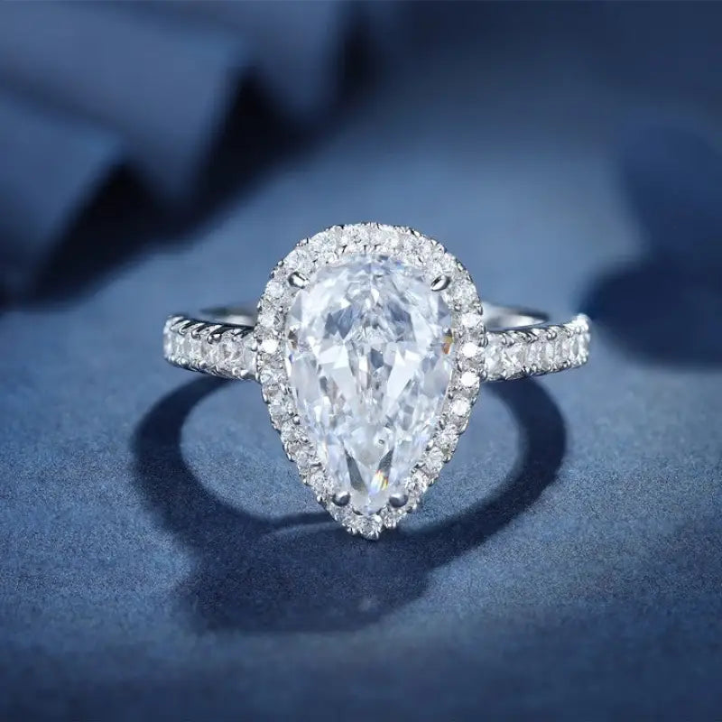 Pear-shaped diamond engagement ring with a halo setting and pavé band.