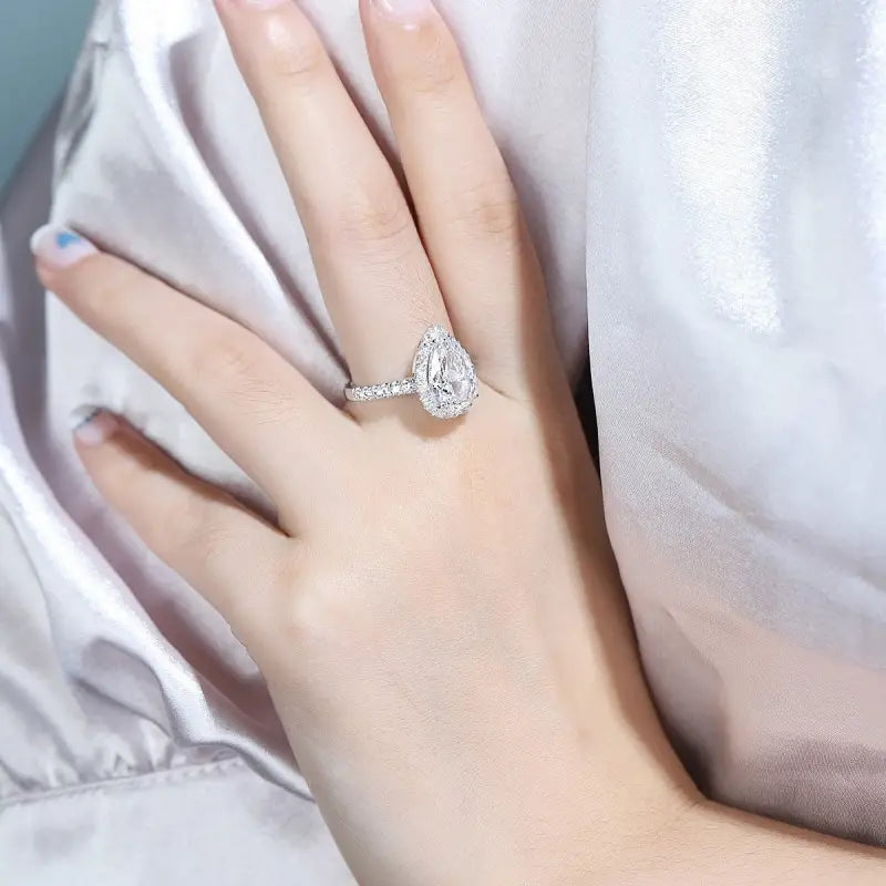 Teardrop-shaped diamond engagement ring on a woman’s finger.