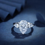 Load image into Gallery viewer, Pear-shaped diamond engagement ring with side stones set in a silver or white gold band.
