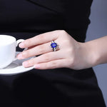 Load image into Gallery viewer, Sapphire ring with diamond accents on a hand holding a white cup.
