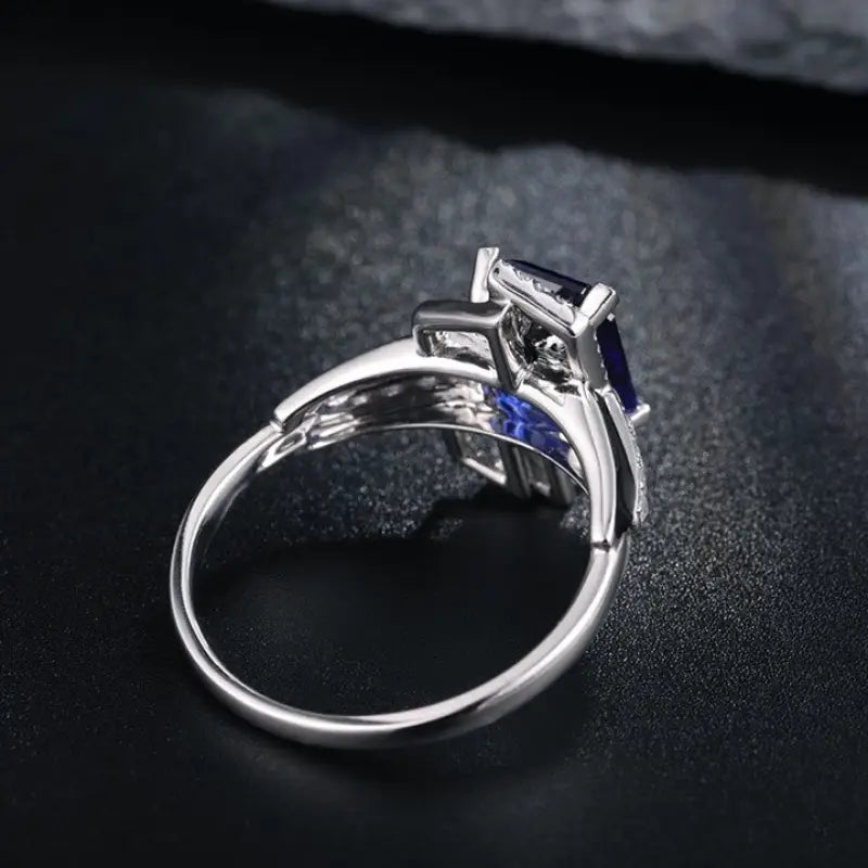 Silver engagement ring with a square-cut blue gemstone in a prong setting.