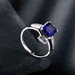 Load image into Gallery viewer, Silver ring featuring a square-cut blue sapphire gemstone and small diamonds.
