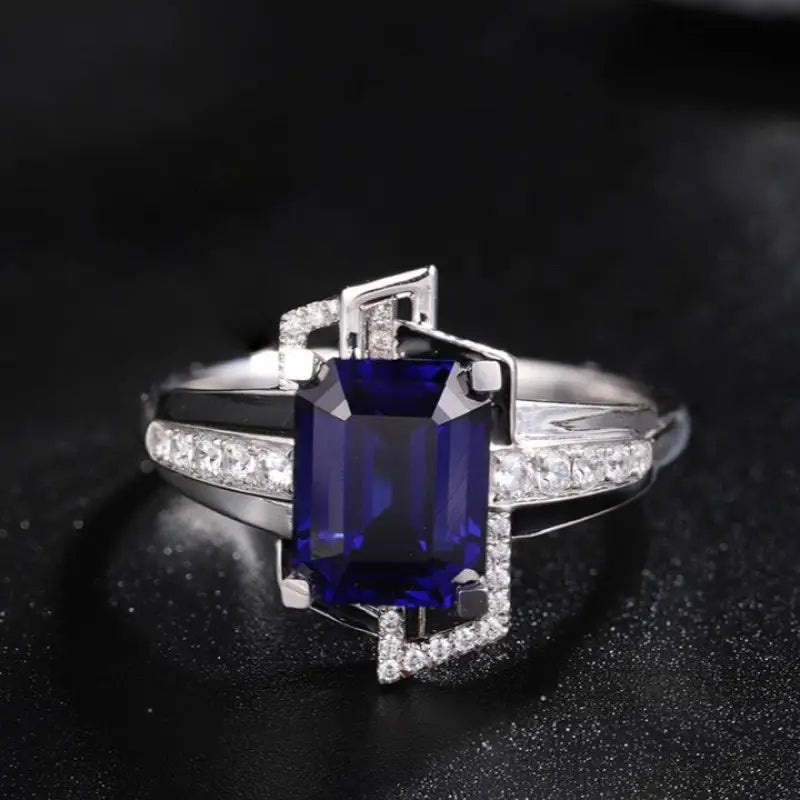 Elegant silver ring featuring a deep blue rectangular gemstone surrounded by small diamonds.