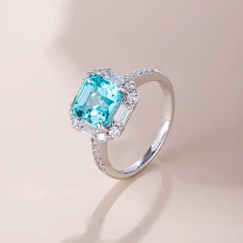 Elegant silver ring featuring a square-cut aquamarine gemstone surrounded by small diamonds.