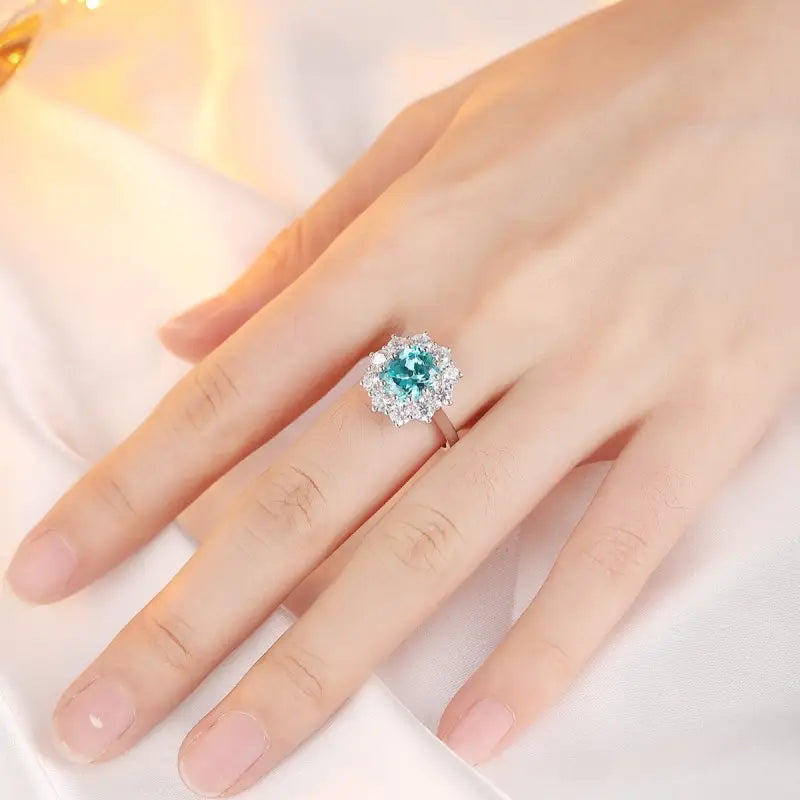 Ornate ring featuring a teal gemstone surrounded by smaller clear stones.