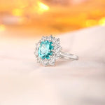 Load image into Gallery viewer, Elegant silver ring featuring a central oval aquamarine gemstone surrounded by small diamonds.
