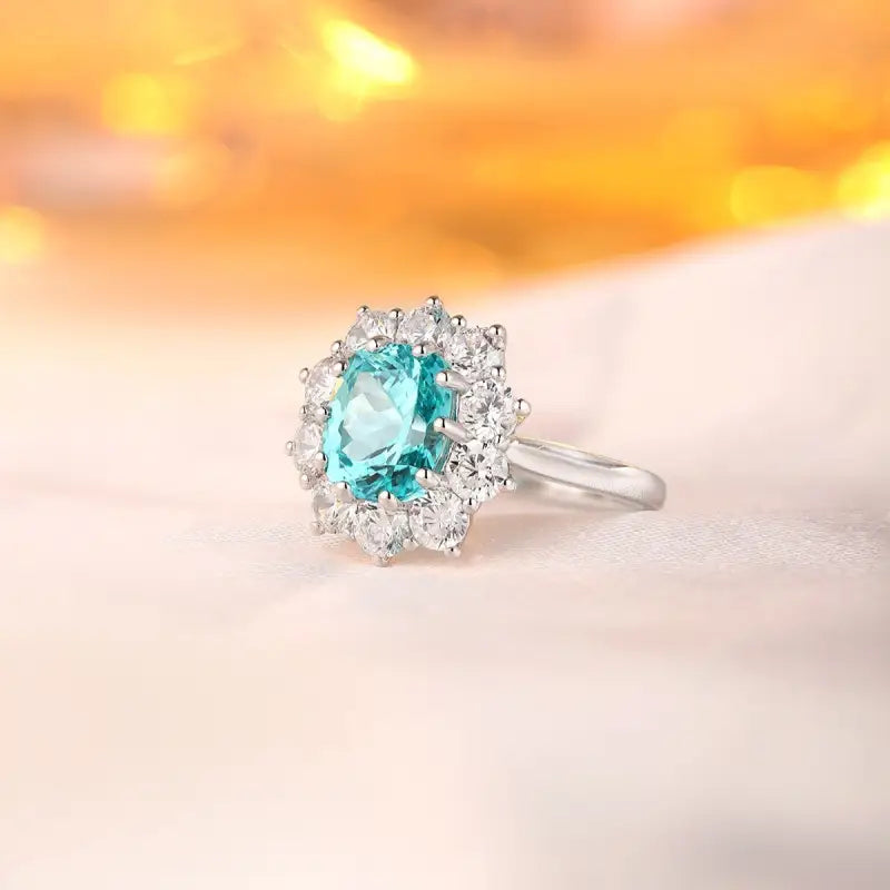 Elegant silver ring featuring a central oval aquamarine gemstone surrounded by small diamonds.