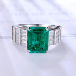 Load image into Gallery viewer, Emerald-cut green gemstone ring with baguette diamond side stones set in a silver or white gold band.
