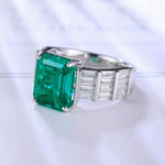 Load image into Gallery viewer, Emerald-cut green gemstone ring with diamond accents on a silver band.
