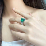 Load image into Gallery viewer, Emerald-cut green gemstone ring with diamond accents on a silver or white gold band.
