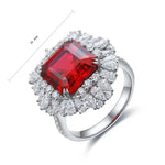 Load image into Gallery viewer, Ornate silver ring featuring a prominent square-cut ruby surrounded by diamond accents.
