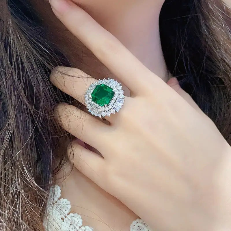 Emerald and diamond ring on a person’s finger.