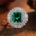 Load image into Gallery viewer, Ornate ring featuring a square-cut emerald surrounded by diamonds.
