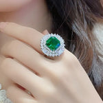 Load image into Gallery viewer, Ornate ring featuring a vibrant emerald-green gemstone surrounded by diamond accents.
