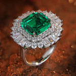 Load image into Gallery viewer, Ornate ring featuring a square-cut emerald surrounded by diamonds.
