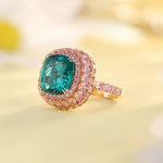 Load image into Gallery viewer, Ornate ring featuring a cushion-cut emerald surrounded by pink gemstones in a rose gold setting.
