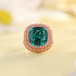 Load image into Gallery viewer, Emerald-colored gemstone ring surrounded by smaller pink stones in a gold setting.
