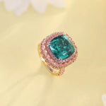 Load image into Gallery viewer, Ornate ring featuring a square-cut emerald surrounded by pink diamonds.
