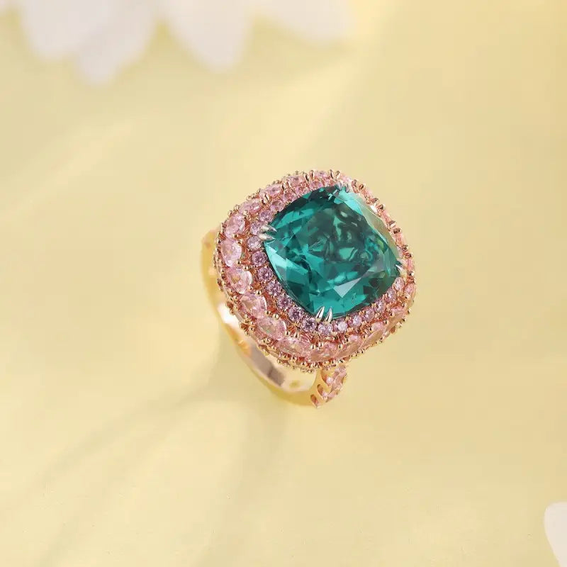 Ornate ring featuring a square-cut emerald surrounded by pink diamonds.