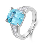 Load image into Gallery viewer, Silver ring featuring a cushion-cut blue topaz gemstone and diamond accents on the band.
