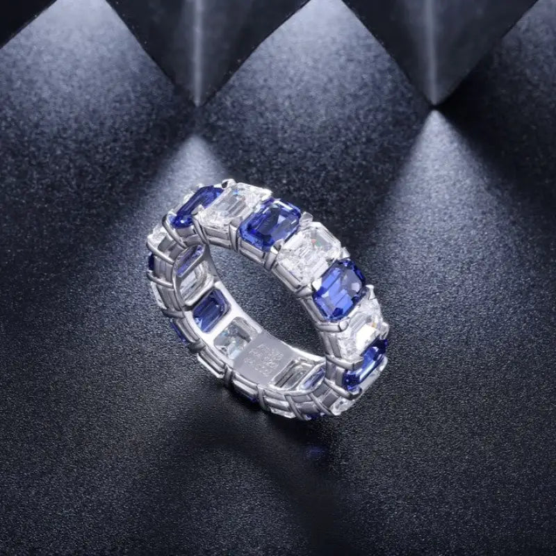 Elegant ring featuring alternating blue sapphires and clear diamonds set in a white metal band.