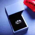 Load image into Gallery viewer, Diamond and sapphire eternity ring in an open jewelry box.
