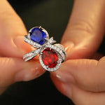 Load image into Gallery viewer, Ornate ring featuring two large gemstones, one blue and one red, surrounded by smaller diamonds in a swirling design.
