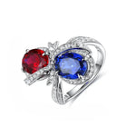 Load image into Gallery viewer, Elegant silver ring featuring a red gemstone and a blue gemstone accented with small diamonds.
